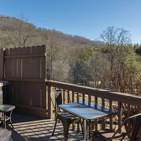 The back deck features a hot tub, a metal table, and a propane grill!